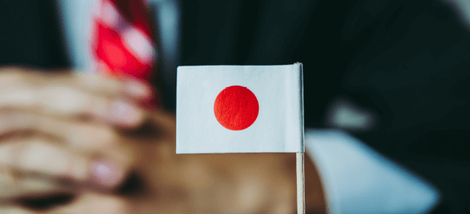日本国旗の後ろに手組んでる男性
